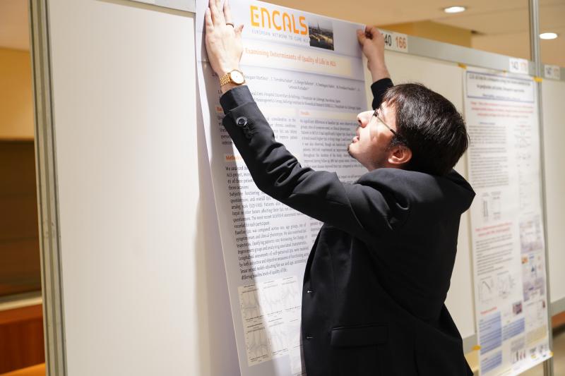 Alejandro Caravaca Puchades mounting the quality-of-life poster on the board at the ENCALS Meeting 2025